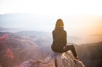 women dressed in black sitting on a mountain peak - Our Mental Well-Being